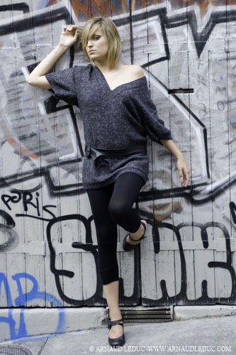 Manon, gagnante du concours 25 ans Nana, pose dans une rue de Marseille devant une porte taguée, en pul échancré gris à paillettes legging et escarpins plats noirs